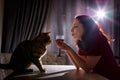 Lonely beautiful middle aged woman alone in the dark kitchen drinking red wine in the evening with her cat Royalty Free Stock Photo