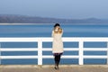 Lonely beautiful sad girl is standing on the pier on a sunny warm autumn evening at the sea