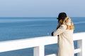 Lonely beautiful sad girl is standing on the pier on a sunny warm autumn evening at the sea