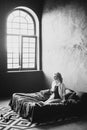 Lonely beautiful woman in the bedroom with large windows on the bed with a glass of wine relaxes. Black and white art photo in a Royalty Free Stock Photo