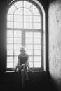 Lonely beautiful woman blonde sits at home at the window. Black and white art photo. Soft selective focus