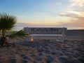 Lonely bench on the beach looking to the horizon, tranquility concept, Where it is written, `with you here and now` Royalty Free Stock Photo