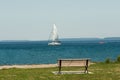 Lonely bench on the beach and a yacht on the horizon