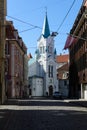 Lonely bicycle rider at empty street of Old Riga Town with sharply white Our Lady of Sorrows Church