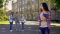 Lonely biracial girl standing alone, upset about mockery and jokes of classmates