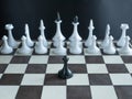 Lonely black pawn standing alone against whole army of white figures on chess board. concept depict one man army famous Martin Royalty Free Stock Photo