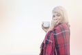 Lonely blond woman on the beach with cup of hot drink, warm red plaid Royalty Free Stock Photo