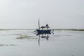 Lonely blue boat floating in the middle of the ocean during low tide Royalty Free Stock Photo