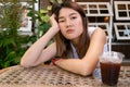 Lonely bored Asian woman waiting for her friend alone in the coffee shop. Royalty Free Stock Photo