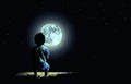 Lonely boy looking at the moon at night