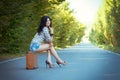 Lonely brunette girl sits on an old suitcase in the middle of th Royalty Free Stock Photo