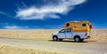Lonely camper truck van on dirt track road in white salt flat desert, blue sky - Salar de Atacama, Chile