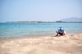 Lonely child girl playing with white sand on sea beach on background of blue sky, clear water and distant shore. Summer Royalty Free Stock Photo