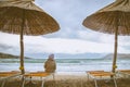 Lonely child in stormy weather sittin in sunbed under parasol in the beach Royalty Free Stock Photo