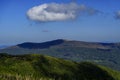 Lonely cloud drifting above forested mountain ridges in deep blue sky Royalty Free Stock Photo