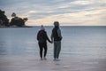 Lonely couple standing by the shore at the Mulini beach, Rovinj, during cold, winter season, watching the calm sea at sunset