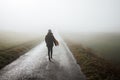 Lonely courageous woman walks on empty road in fog Royalty Free Stock Photo