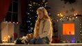 Lonely cute girl with teddy-bear sitting near Christmas tree, missing parents Royalty Free Stock Photo