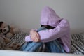 Lonely depressed teenage girl wearing hood sitting on bed alone Royalty Free Stock Photo