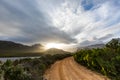 Lonely dirt road leading into a mountain range at sunset Royalty Free Stock Photo