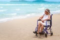 Lonely disabled senior elderly woman in wheelchair on tropical sand beach, Asian grandma looking at summer blue sea Royalty Free Stock Photo