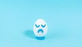 Lonely egg with a sad expression close up. The concept of a pessimistic outlook on life. Blue background Royalty Free Stock Photo