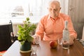 Lonely Elderly Drinking Wine at the Wooden Table