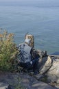 Lonely elderly fisherman in a jacket and a cap on a stone river bank and fishing