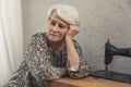 lonely European elderly lady thinking about sad things and touching her grey hair