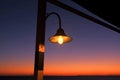 the evening at the mediterranean sea, shines lonely lamp on the post on the background sunset and stripes dark sea Royalty Free Stock Photo