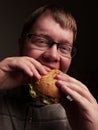 Lonely fat guy eating hamburger. Bad eating habits. Closeup. Royalty Free Stock Photo