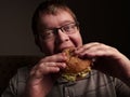 Lonely fat guy eating hamburger. Bad eating habits. Closeup. Royalty Free Stock Photo