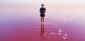 A lonely figure of a man against the background of a huge pink lake.