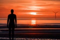 A lonely figure stands silent in the sea looking out towards to the horizon