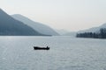 Lonely fisheing boat on a lake of Lugano, Switzerland, with mountains