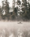 A lonely fisherman in a boat on the river on a foggy morning.
