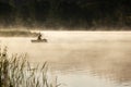 Lonely fisherman fishes in beautiful lake shining in morning mist Royalty Free Stock Photo