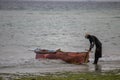 Lonely fisherman at the Mozambique sandy beach preparing boat to go for sailing and fishing Royalty Free Stock Photo