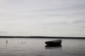 Lonely fishing boat docked in calm lake. wooden fishing boat in a still lake water. image of wooden fishing boat moored on the sho Royalty Free Stock Photo