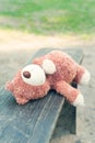 Lonely forgotten teddy bear toy lying on the bench.