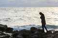 Lonely girl in a depressed mood walking along a rocky seashore Royalty Free Stock Photo