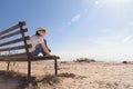 Lonely girl with glasses siting on a bench on the coast and looks sadly into the distance. Royalty Free Stock Photo