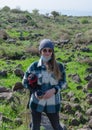 Lonely girl in a knitted hat and a plaid coat posing in front of the camera on the background of nature