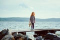 A lonely girl with a plush Bunny is standing on the pier and loo Royalty Free Stock Photo