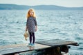 A lonely girl with a plush Bunny is standing on the pier and loo Royalty Free Stock Photo