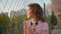 Lonely girl posing sunlight chewing gum close up. Teenager leaning on fence net Royalty Free Stock Photo