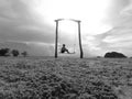 Lonely girl sit on swings at low tide beach