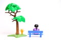 Lonely girl sits on a bench near a tree children's figurines toys