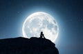 Lonely girl sitting alone on the cliff and looking to the moon