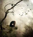 Lonely girl sitting on a rock in sorrow Royalty Free Stock Photo